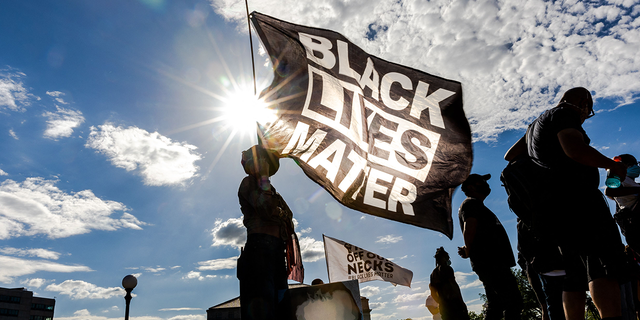 Une femme tient un drapeau Black Lives Matter lors d'un événement en souvenir de George Floyd.