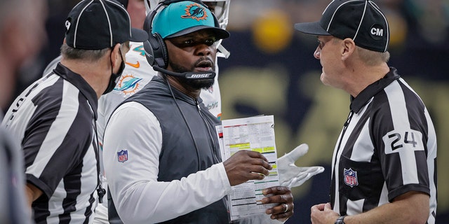 FILE - Miami Dolphins head coach Brian Flores, center, talks to down judge David Oliver (24) during the first half of an NFL football game against the New Orleans Saints Monday, Dec. 27, 2021, in New Orleans.