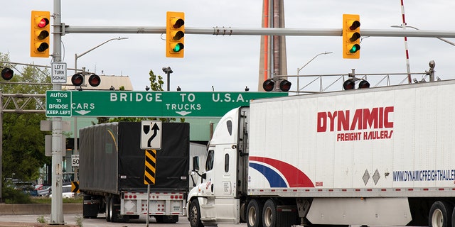 Transport trucks pass under a "Bridge To USA" at the entrance to the Ambassador Bridge, US-Canada border crossing. (Windsor, ON)