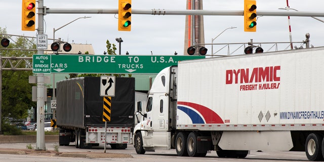 Transport trucks pass under a "Bridge To USA" at the entrance to the Ambassador Bridge, US-Canada border crossing. (Windsor, ON)