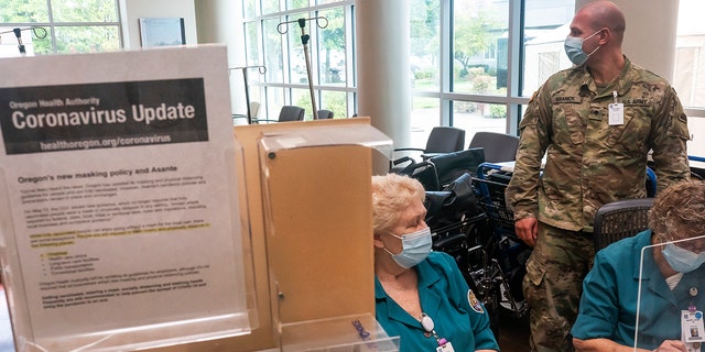 GRANTS SKIP, OR - SEP 9: (EDITOR'S NOTE: EDITORIAL USE ONLY.) An Oregon National Guardsman works with hospital staff at the reception desk at Three Rivers Asante Medical Center on September 9, 2021 in Grants Pass, Oregon.  Like many hospitals in the state, Three Rivers Asante is facing the biggest resurgence of the COVID-19 pandemic, forcing them to operate well beyond their capacity.  (Photo by Nathan Howard/Getty Images)