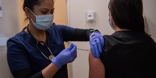A health care worker administers a third dose of the Moderna COVID-19 vaccine at the CareNow Denver University urgent care center in Denver, Colorado, on Tuesday, Nov. 16, 2021.