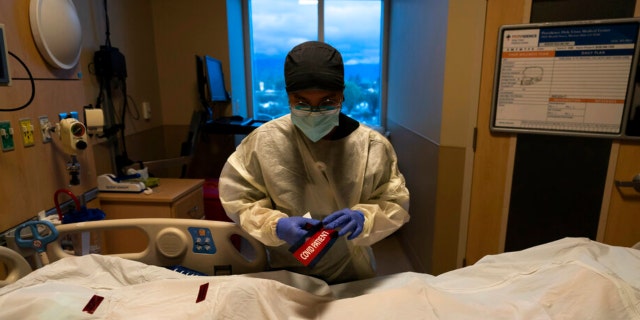 Registered nurse Bryan Hofilena attaches a "COVID Patient" sticker on a body bag