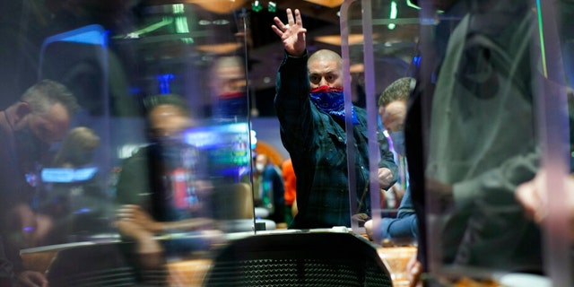 People play craps while wearing masks and between plexiglas partitions as a precaution against the coronavirus at the opening night of the Mohegan Sun Casino at Virgin Hotels Las Vegas in Las Vegas on March 25, 2021.
