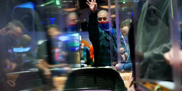 People play craps while wearing masks and between plexiglas partitions as a precaution against the coronavirus at the opening night of the Mohegan Sun Casino at Virgin Hotels Las Vegas in Las Vegas on March 25, 2021.