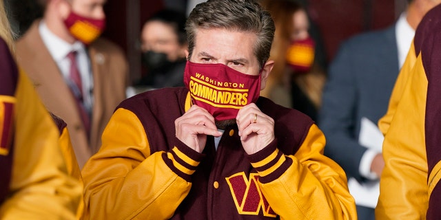 Dan Snyder, centro, copropietario y codirector ejecutivo de los Washington Commanders, ajusta su máscara cuando llega para revelar la nueva identidad de su equipo de fútbol americano de la NFL, el miércoles 2 de febrero de 2022, en Landover, Maryland.