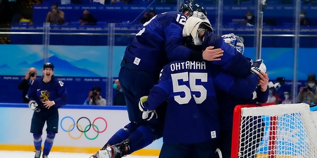 Finland's Marko Anttila (12) jumps on Atte Ohtamaa (55) and goalkeeper Harri Sateri after Finland beat Russian Olympic Committee to win the men's gold medal hockey game at the 2022 冬奥会, 星期日, 二月. 20, 2022, 在北京. 