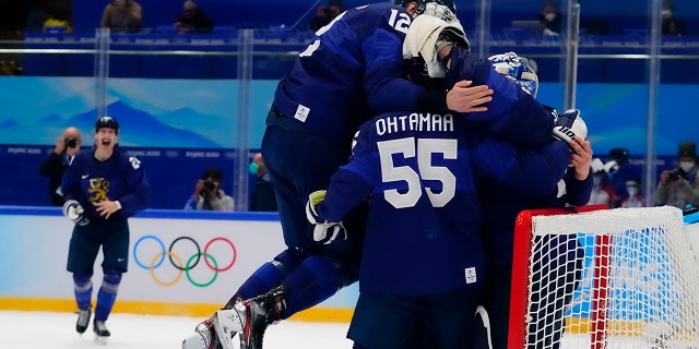 Finland's Marko Anttila (12) jumps on Atte Ohtamaa (55) and goalkeeper Harri Sateri after Finland beat Russian Olympic Committee to win the men's gold medal hockey game at the 2022 冬奥会, 星期日, 二月. 20, 2022, 在北京.