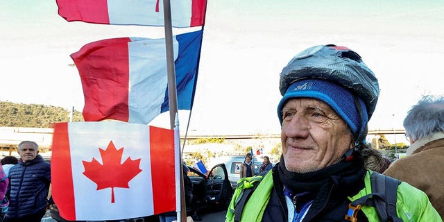A French activist holds a Canadian flag before the start of their "Convoi de la liberte" (The Freedom Convoy), a vehicular convoy protest converging on Paris to protest coronavirus disease (COVID-19) vaccine and restrictions in Nice, France, February 9, 2022. 