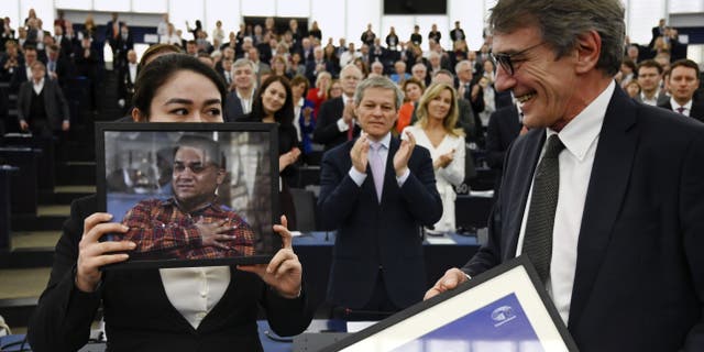 TOPSHOT - European Parliament President David-Maria Sassoli (R) stands next to Jewher Ilham, daughter of Ilham Tohti, Uyghur economist and human rights activist, holding a portrait of her father during the award ceremony for his 2019 European Parliament's Sakharov human rights prize at the European Parliament in Strasbourg, eastern France, on December 18, 2019. (Photo by FREDERICK FLORIN / AFP) (Photo by FREDERICK FLORIN/AFP via Getty Images)