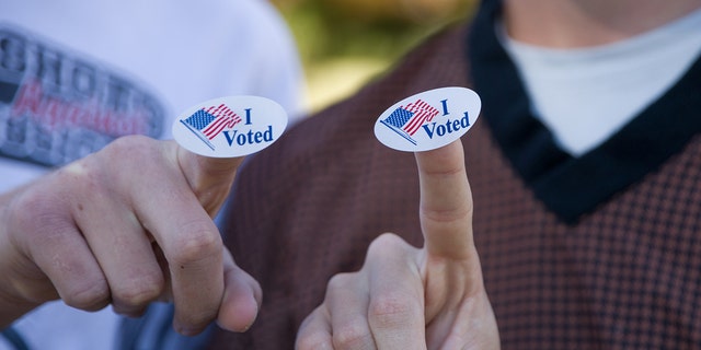 Young voters show "I Voted" stickers after voting at a polling station in Plano, Texas, Nov. 3, 2020.