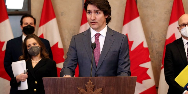 Justin Trudeau at lectern, Canada flags behind him