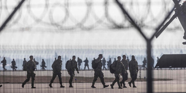 TOPSHOT - Soldiers of US Army troops walk on the tarmac at Rzeszow-Jasionka Airport, south eastern Poland, on February 16, 2022.