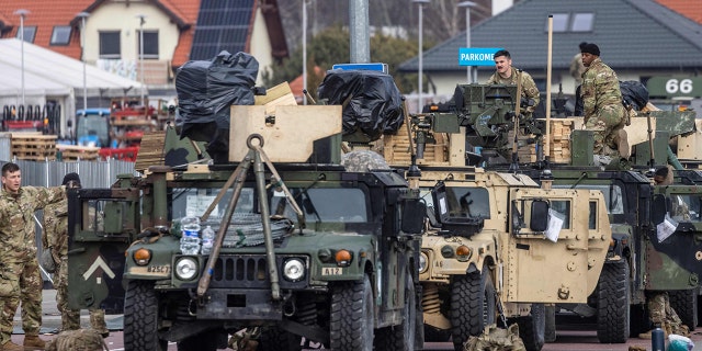 US soldiers work on their vehicles at a temporary base installed close to the Rzeszow-Jasionka Airport, south eastern Poland, February 16, 2022. (Photo by WOJTEK RADWANSKI/AFP via Getty Images)