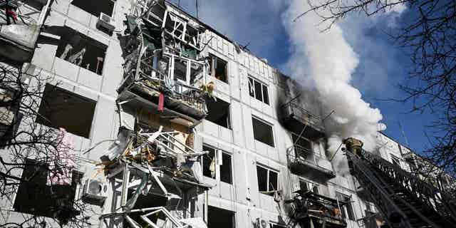 Firefighters work on a fire on a building after bombings on the eastern Ukraine town of Chuguiv on February 24, 2022, as Russian armed forces are trying to invade Ukraine from several directions, using rocket systems and helicopters to attack Ukrainian position in the south, the border guard service said. 