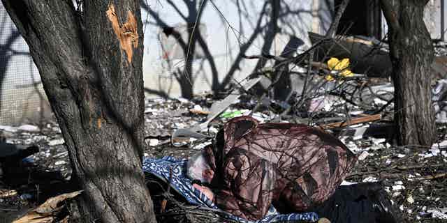 Мужчина реагирует на тело родственника возле разрушенного здания после бомбардировки восточноукраинского города Чугов 24 февраля 2022 года.