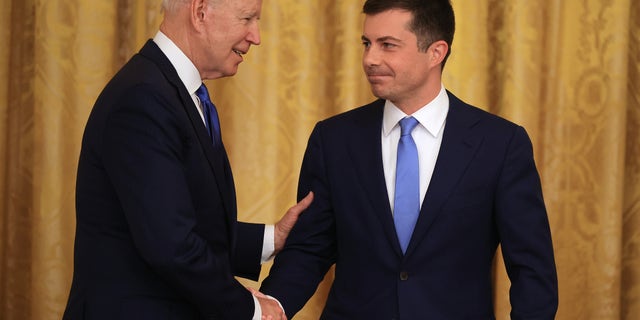 President Joe Biden shakes hands with Transportation Secretary Pete Buttigieg.