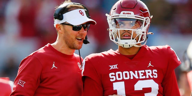 Head coach Lincoln Riley smiles with quarterback Caleb Williams #13 of the Oklahoma Sooners after his 74-yard touchdown run against the Iowa State Cyclones in the first quarter at Gaylord Family Oklahoma Memorial Stadium on November 20, 2021 in Norman, Oklahoma. The Sooners won 28-21.