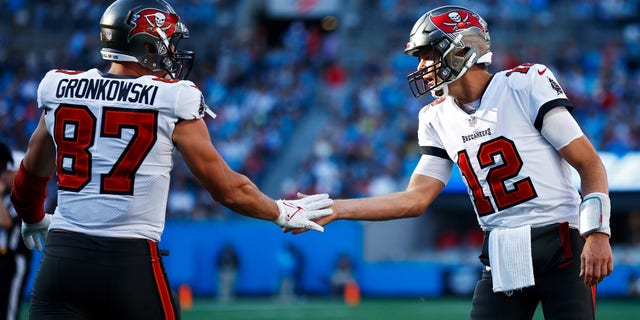 Tom Brady #12 and Rob Gronkowski #87 of the Tampa Bay Buccaneers react after a touchdown during the third quarter in the game against the Carolina Panthers at Bank of America Stadium on December 26, 2021 in Charlotte, North Carolina. 