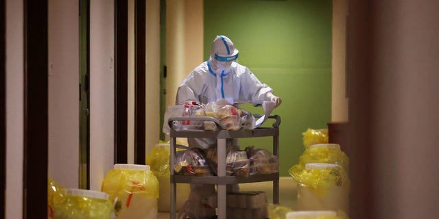 A volunteer is seen dispensing food and water inside the Shuanglong Hotel, which is serving as an isolation facility during the Winter Olympics, on Feb. 6, 2022, in Zhangjiakou, China. 