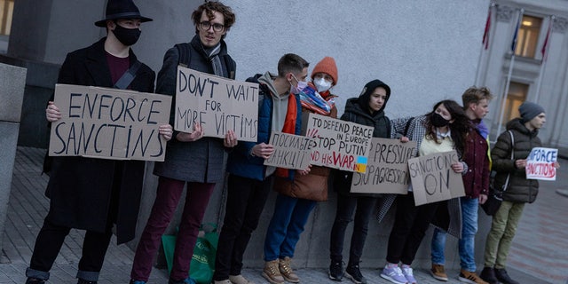 A group of people hold signs at the front of the Ukrainian Foreign Ministry during a protest calling for the European Union to impose additional sanctions against Russia on February 21, 2022 in Kyiv, Ukraine.  (Photo by Chris McGrath/Getty Images)