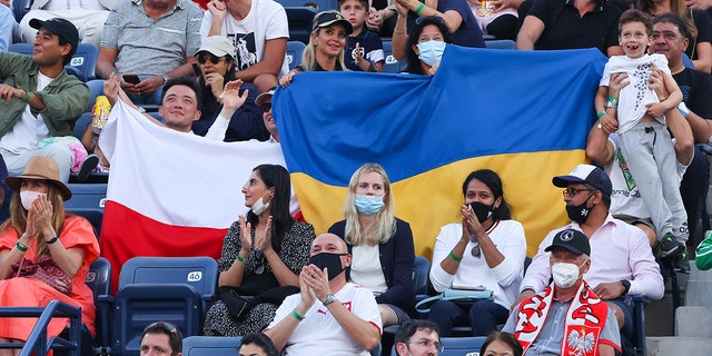حمل أعضاء الحشد أعلامًا ، بما في ذلك أعلام أوكرانيا ، خلال مباراة نصف النهائي بين البولندي هوبرت هاركوكس والروسي أندريه روبليف في 25 فبراير 2022 في دبي ، الإمارات العربية المتحدة. 