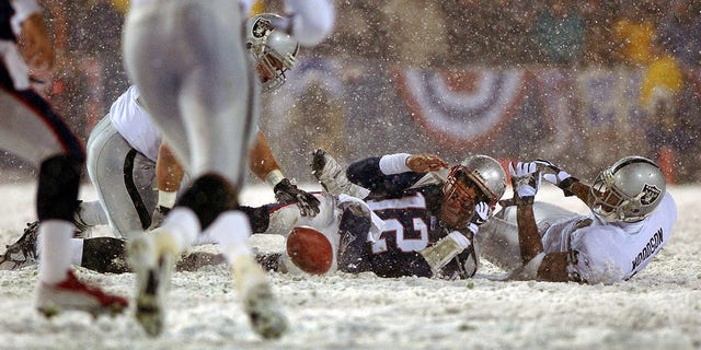 Patriots quarterback Tom Brady loses the ball after being hit by the Oakland Raiders Charles Woodson on Jan. 19, 2002, en Foxborough, Massachusetts. The fumble was ruled an incomplete pass, giving New England another chance.