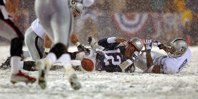 Patriots quarterback Tom Brady loses the ball after being hit by the Oakland Raiders' Charles Woodson. The ball was recovered by Oakland but it was ruled an incomplete pass, giving the Patriots another chance.