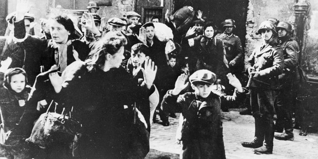 (Original Caption) 12/27/1945-Warsaw, Poland-Arms raised above their heads, white faces with fear. A group of Polish women and children waits to be led off by storm troopers during the Nazi destruction of Warsaw in 1943. Photo taken by an S.S. Commander. A report to his superiors was introduced at the Nuremberg trials as evidence of Nazi terrorism in the Polish capital. BPA 2 #5611