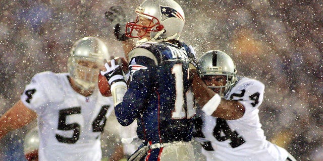 New England Patriots quarterback Tom Brady takes a hit from Charles Woodson of the Oakland Raiders during the AFC playoff game Jan. 19, 2002, in Foxboro, Massachusetts.