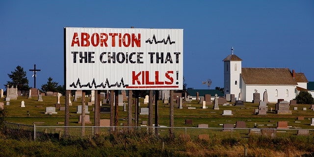 A billboard with the text, "Abortion: The choice that kills," is seen inside a cemetery in Kimball, South Dakota