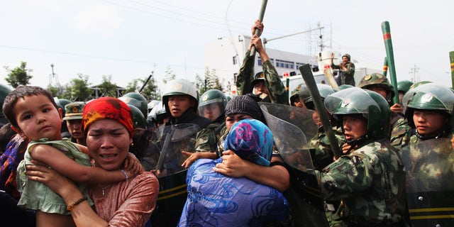 Chinese police push Uyghur women during a protest in Urumqi, the capital of the Xinjiang Uyghur Autonomous Region in China. (Guang Niu / Getty Images / File)