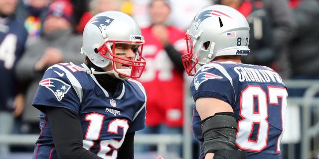 Rob Kronkowski, do New England Patriots, responde com # 87 Tom Brady # 12 depois de receber um passe para touchdown durante o segundo quarto do jogo contra o Buffalo Pills no Gillette Stadium em 24 de dezembro de 2017 em Foxboro, Massachusetts.  