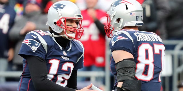 Rob Kronkowski von den New England Patriots antwortet mit # 87 Tom Brady # 12, nachdem er im zweiten Viertel des Spiels gegen Buffalo Pills im Gillette Stadium am 24. Dezember 2017 in Foxboro, Massachusetts, einen Touchdown-Pass gefangen hat.  