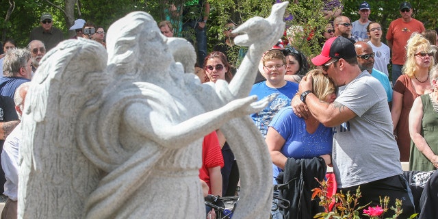 Lou Diamond embraces his girlfriend Lisa Sherman as she becomes emotional during the dedication ceremony for the memorial park at the site of the Station nightclub fire in West Warwick, Rhode Island, May 21, 2017. Sherman lost two cousins in the fire.