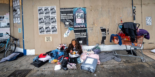 FILE – Deborah Knapp, ouderdom 51, uses an awning from a business in the 14500 block of Victory Blvd. to keep her and her belongings dry from the rain in Van Nuys, Kalifornië, op Desember 27, 2021. Knapp has been living on the street for years.