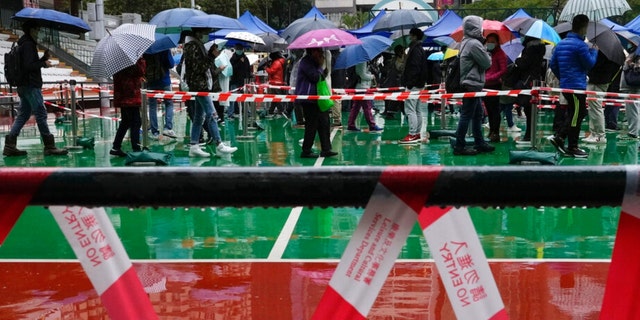 Despite the rain, residents line up to get tested for the coronavirus at a temporary testing center in Hong Kong Feb. 21, 2022.