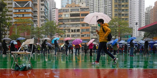 Residents line up to get tested for the coronavirus at a temporary testing center despite the rain in Hong Kong, Tuesday, Feb. 22, 2022.  