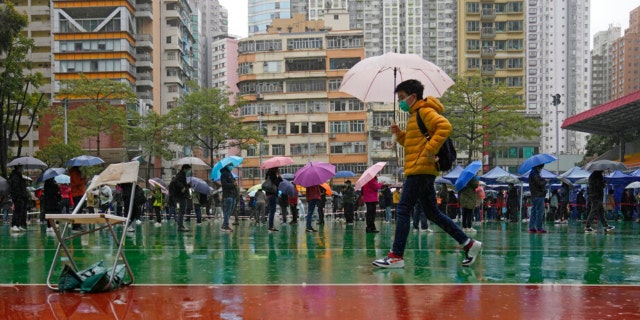 Residents line up to get tested for the coronavirus at a temporary testing center despite the rain in Hong Kong, Tuesday, Feb. 22, 2022.