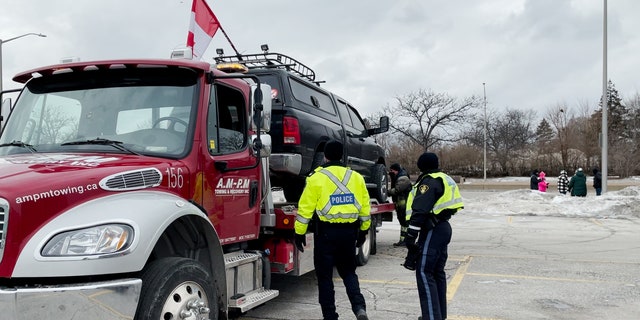 A car with a Canadian flag is towed on Sunday morning near the Ambassador Bridge in Windsor, Canada