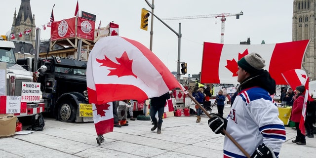 Man waves a Canadian flag on the 20th day of the Freedom Convoy in Ottawa.