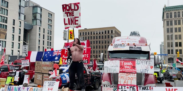 A Freedom Convoy demonstrator holds a "Hold The Line" sign while dancing in Ottawa, Canada.