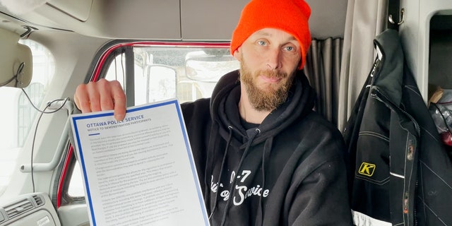 Canadian trucker Mike Anderson holds up the notice warning demonstrators to leave or potentially face arrest.