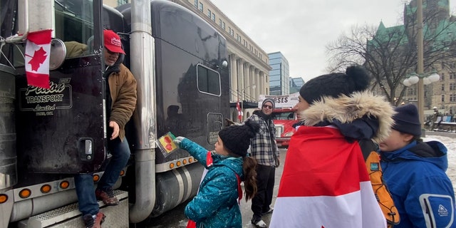 A girl and her family walk through the line of truckers, handing out thank you notes