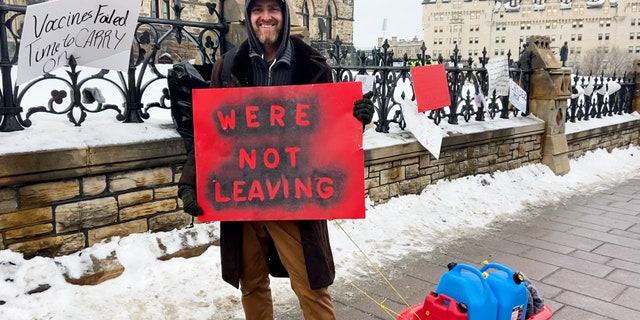 Man holds a sign that says, 