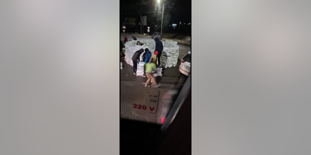 People stacking sandbags on the road between Kyiv and Poland on Friday, Feb. 25, 2022.