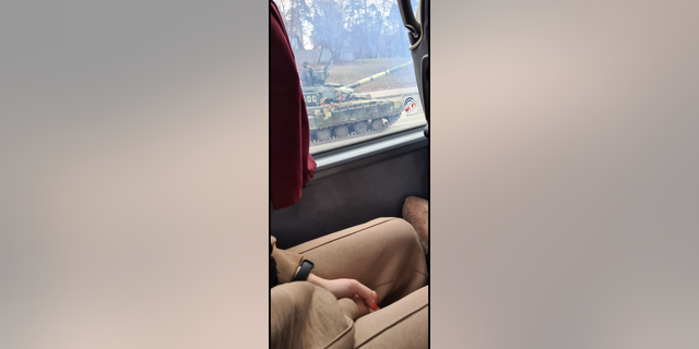 A Ukrainian tank passes a bus carrying travelers from Kyiv toward the border with Poland on Friday, Feb. 25, 2022. Hours later, fighting had reached Ukraine's capital city amid Russia's invasion of the country.