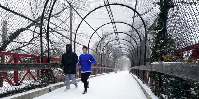 Runners run on a snow covered Monon Trial, Thursday, Feb. 3, 2022, in Indianapolis. A major winter storm with millions of Americans in its path is spreading rain, freezing rain and heavy snow further across the country.