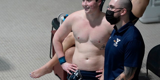 Yale Isaac Hennig가 2022년 2월 16일 수요일 매사추세츠주 캠브리지의 하버드 대학교에서 열린 아이비리그 여자 수영 및 다이빙 챔피언십 팀 계주 경기 전에 코치와 이야기하면서 미소를 짓고 있습니다.