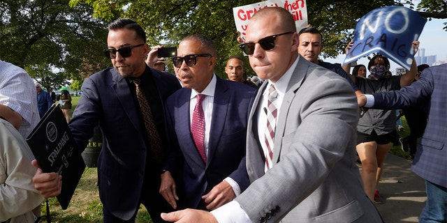 FILE - James Craig, center, a former Detroit Police chief, is escorted past protesters at a news conference on Belle Isle in Detroit, Tuesday, Sept. 14, 2021, where he announced he is a Republican candidate for governor of Michigan. 